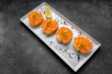 Yeşil soğanlı ve limonlu bir tabakta kırmızı havyar.