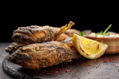 Koyu bir arka planda, limon ve otlarla kızartılmış balık Karadeniz kebabı.