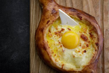Adjarian Khachapuri Ahşap bir tahtada, karanlık bir arka planda
