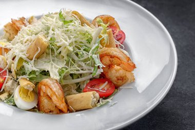 Karidesli Sezar salatası, bir tabakta, koyu arkaplanda. Metin için yer
