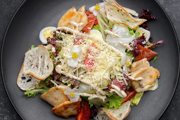 Caesar Salat Mit Huhn Und Essbaren Blumen Auf Schwarzem Teller — Stockfoto