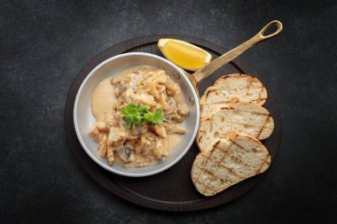 Limonlu ve tostlu krema soslu Rapani kızartma tavasında, siyah arka planda.