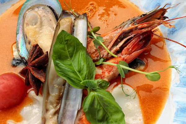 Deniz mahsullü Bouillabaisse çorbası, midye, karides, kalamar. Bir tabakta, karanlık bir arka planda.