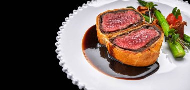 Mantarlı sığır eti, kuşkonmaz ve siyah arka planda baharatlı Razmarin soslu siyah mantar.