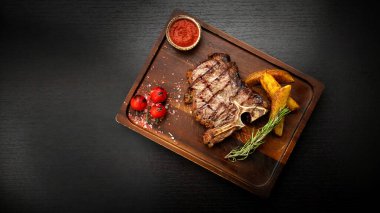 Tahta bir tahtanın üzerinde soslu ve patatesli biftek.