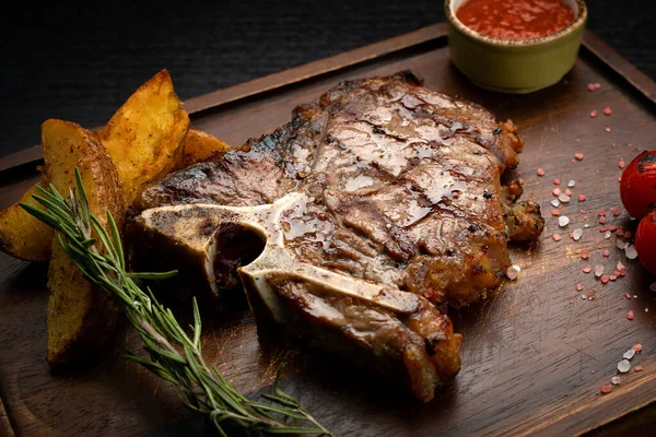 Tahta bir tahtanın üzerinde soslu ve patatesli biftek. — Stok fotoğraf