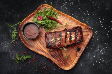 Ahşap bir tahtanın üzerinde soslu ve otlu ızgara pirzola.