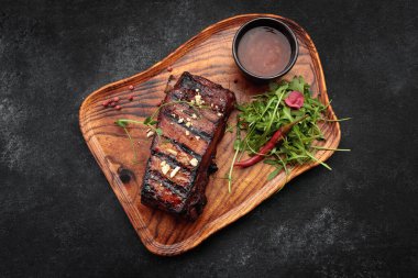 Ahşap bir tahtanın üzerinde soslu ve otlu ızgara pirzola.