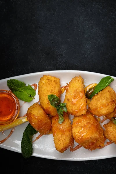 Peynirli nugget. Nane ve reçel, bir tabakta, karanlık bir arka planda.