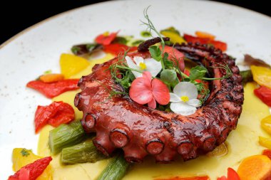 Grilled octopus tentacles on a plate with asparagus and sauce