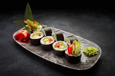 Suşi Yasai 'yi bir tabakta yuvarlıyor, karanlık bir arka planda.