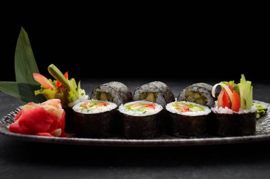 Suşi Yasai 'yi bir tabakta yuvarlıyor, karanlık bir arka planda.