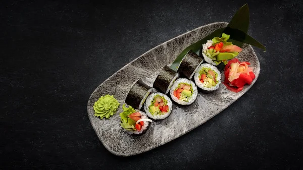 Suşi Yasai 'yi bir tabakta yuvarlıyor, karanlık bir arka planda.