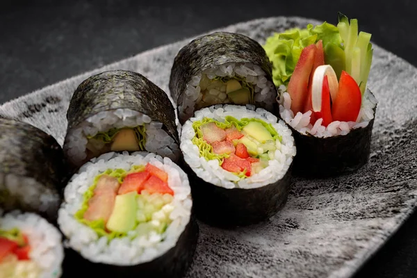Suşi Yasai 'yi bir tabakta yuvarlıyor, karanlık bir arka planda.