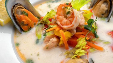 Somon balıklı kremalı balık çorbası ve arka planda deniz ürünleri.