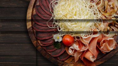 Bira, kurutulmuş mürekkep balığı, basturma, jamon, domuz kulağı ve kiraz domatesleri için ahşap bir arka planda.