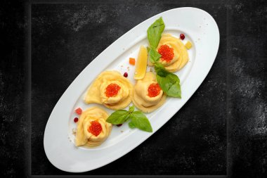 Beyaz tabakta kırmızı havyarlı geleneksel gözleme, fesleğen, koyu arkaplan