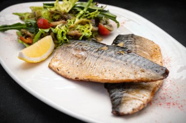 Bir tabakta iki fırında uskumru fileto, kekik, biberiye ve limon.
