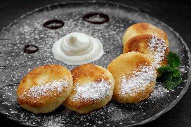 Ekşi krema ve naneli siyah tabakta süzme peynirli kekler.