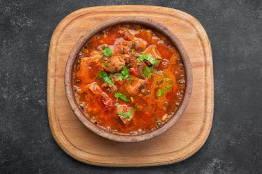 Gürcistan ulusal yemeği Ojakhuri, kilden bir tabakta, tahta bir tahtada, karanlık bir arka planda.