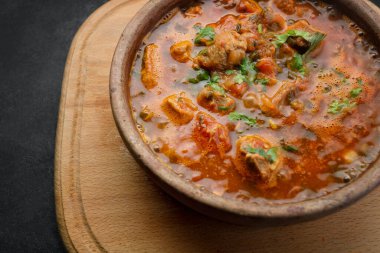 Gürcistan ulusal yemeği Ojakhuri, kilden bir tabakta, tahta bir tahtada, karanlık bir arka planda.