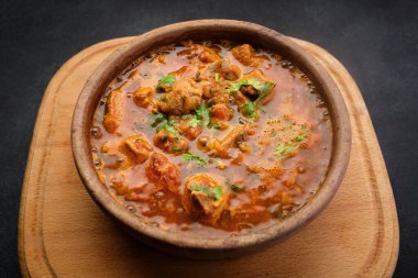 Gürcistan ulusal yemeği Ojakhuri, kilden bir tabakta, tahta bir tahtada, karanlık bir arka planda.