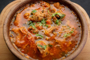 Gürcistan ulusal yemeği Ojakhuri, kilden bir tabakta, tahta bir tahtada, karanlık bir arka planda.