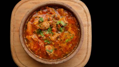 Gürcistan ulusal yemeği Ojakhuri, kilden bir tabakta, tahta bir tahtada, karanlık bir arka planda.