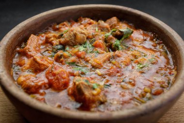 Gürcistan ulusal yemeği Ojakhuri, kilden bir tabakta, tahta bir tahtada, karanlık bir arka planda.