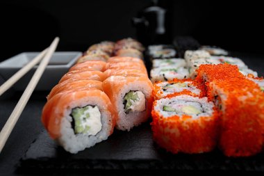 Suşi seti, beş farklı rulodan, koyu bir arka planda.