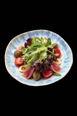 Ton balıklı Nicoise salatası, bir tabakta, koyu arkaplanda. Dikey