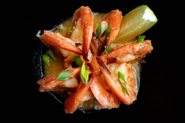 Siyah tabakta limonlu soslu kızarmış karides.