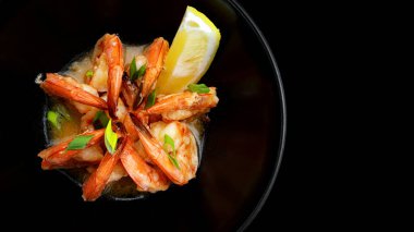 Siyah tabakta limonlu soslu kızarmış karides.