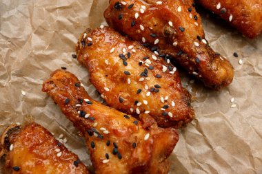 Kraft kağıdında susam tohumuyla kızartılmış tavuk budu ve kanatları.