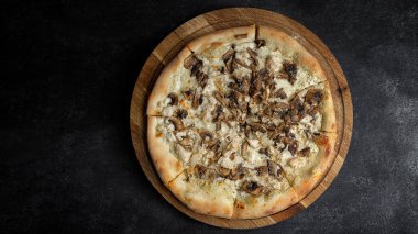 Mantarlı pizza ve ahşap bir tahta üzerinde tavuk, karanlık bir arka planda. Stüdyo ışığı