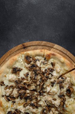 Mantarlı pizza ve ahşap bir tahta üzerinde tavuk, karanlık bir arka planda. Stüdyo ışığı