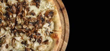 Mantarlı pizza ve ahşap bir tahta üzerinde tavuk, karanlık bir arka planda. Stüdyo ışığı