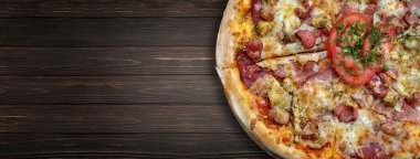 Sosisli, tavuklu, peynirli ve domatesli pizza koyu ahşap arka planda, seçici bir odak ile. Yatay