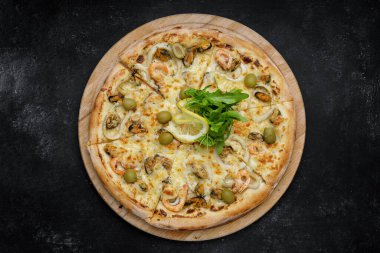Kalamar midyeli, karides zeytinli ve limonlu marinara pizzası. Gri beton üzerinde ahşap bir tahta üzerinde..