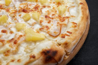 Etli, jambonlu, ananaslı, ahşap bir tahta üzerinde pizza.