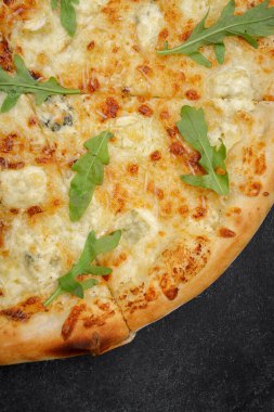 Dört peynirli pizza quattro fromaggi roka yapraklı gri beton üzerinde ahşap bir tahta üzerinde