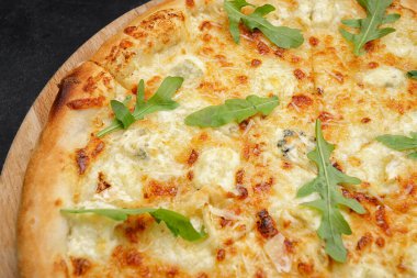Dört peynirli pizza quattro fromaggi roka yapraklı gri beton üzerinde ahşap bir tahta üzerinde