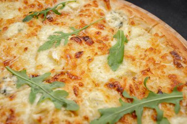 Dört peynirli pizza quattro fromaggi roka yapraklı gri beton üzerinde ahşap bir tahta üzerinde