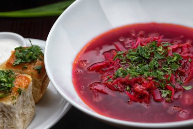 Ukrainian borscht with dill and donuts with garlic on a white plate