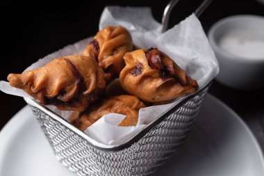 Oriental dish Sambusiki with lamb and sauce on dark background