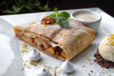 Dessert apple strudel on a plate with sauce and mint