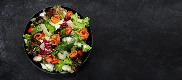Salad with salmon, parmesan cheese, tomatoes and salad mix on a plate