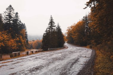 Empty old mountain road during autumn rain along the river
