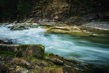 Mountain river among large stones with moss on a long exposure. artistic processing