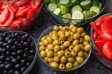Chopped vegetables, cucumbers and tomatoes, olives, on plates, close-up selective focus